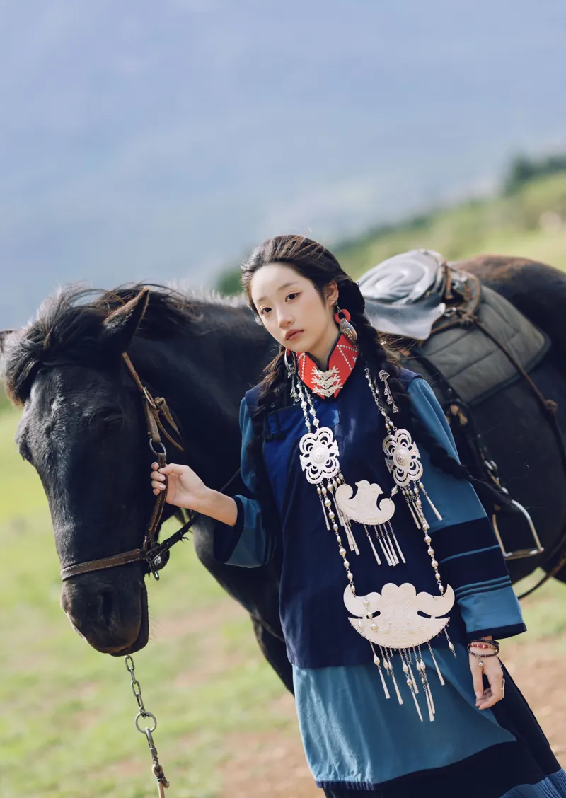 丽江，穿彝族服饰的女孩牵着一匹黑马