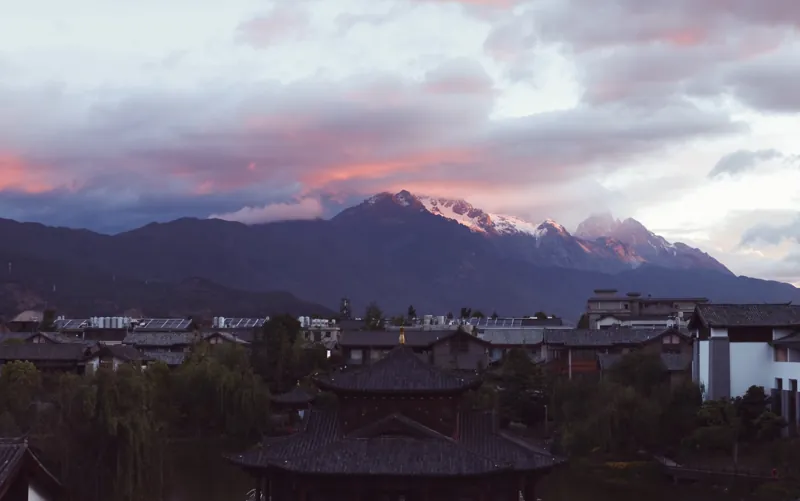 丽江古城屋顶后的雪山和晚霞